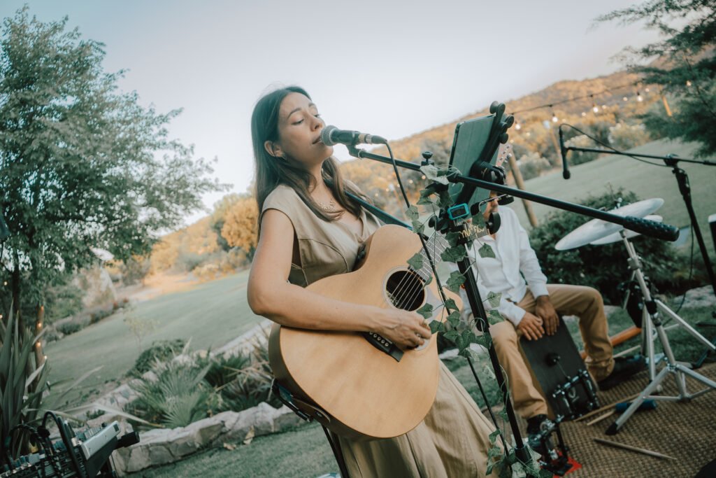 Destination Weddings on the Costa Blanca Tyna Ros singing with acoustic guitar at an outdoor wedding